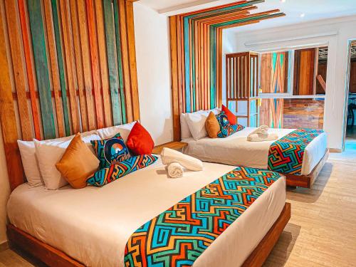 a hotel room with two beds with colorful pillows at In Di House of Reggae Boutique in San Andrés