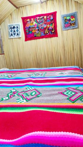 a bed with a red blanket on a wooden table at Uros Maya Lodge in Puno