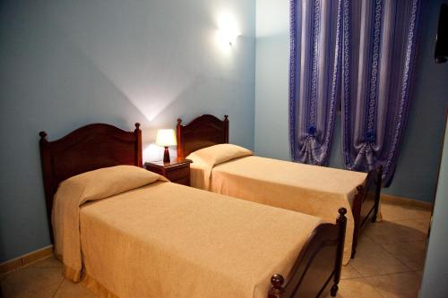 two beds in a room with purple curtains at Villa Musica in Sannicola
