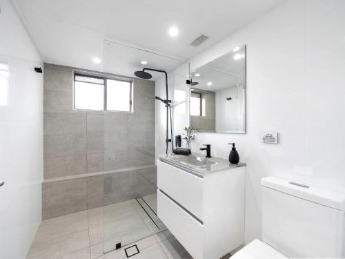 a white bathroom with a shower and a sink at Bayswell by Experience Jervis Bay in Huskisson