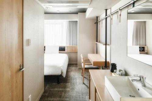 a hotel room with a bed and a sink at REF Matsuyama City Station by VESSEL HOTELS in Matsuyama