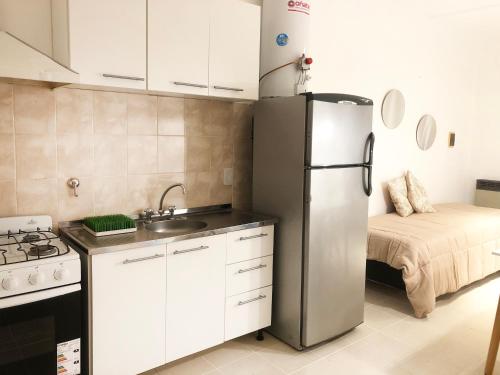 eine Küche mit einem Kühlschrank aus Edelstahl und einem Bett in der Unterkunft RIO 1 Departamento temporario con cochera in Villa María