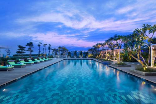 a large swimming pool with chairs and palm trees at Novotel Tangerang in Tangerang