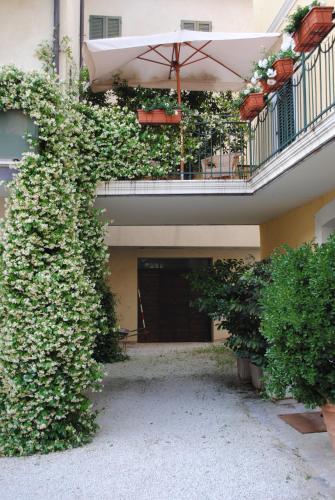 an ivy covered building with an umbrella and a courtyard at Guest Apartament Clarice in Capodacqua di Foligno