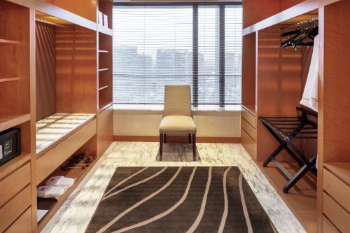 a walk in closet with a chair and a window at Grand Millennium Beijing in Beijing