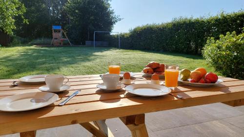 a wooden table with plates of food and orange juice at vakantiewoning met permanent verwarmd zwembad en sauna in Koekelare