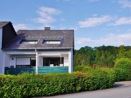una casa blanca con una valla azul y arbustos en Fewo Sauerlandglück mit MeineCardPlus, en Willingen