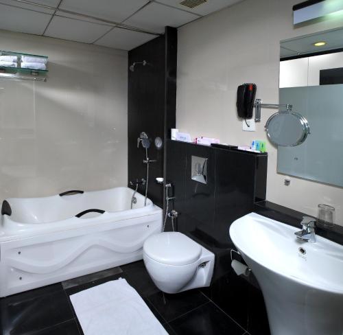 a bathroom with a white tub and a toilet and a sink at Hotel Olive Eva in Kakkanad