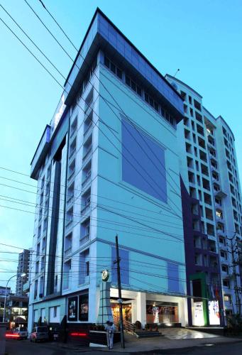 a tall blue building on a city street at Hotel Olive Eva in Kakkanad