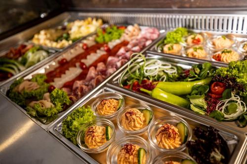 a buffet filled with different types of food in plastic containers at Arena Deluxe & Spa in Szeged