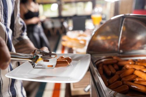 a person is preparing a plate of hot dogs at Arena Deluxe & Spa in Szeged