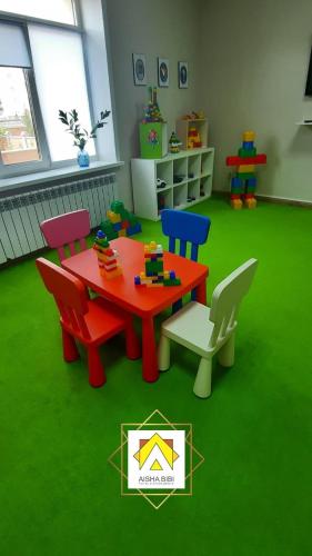 a room with a table and chairs in a room with green carpet at Aisha Bibi Hotel & Spa in Astana