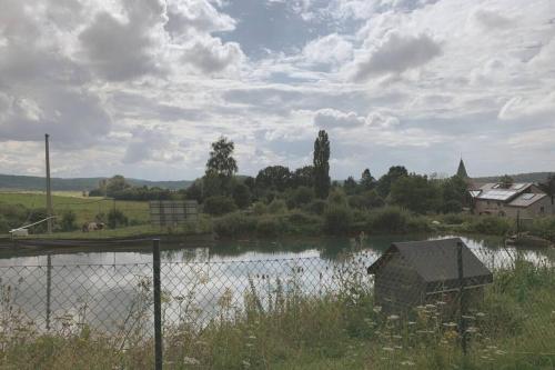 a body of water with a fence in front of it at Au bord du Ny in Hotton