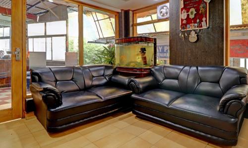 a living room with two leather couches and a fish tank at Sky Pie hotel in Dharamshala