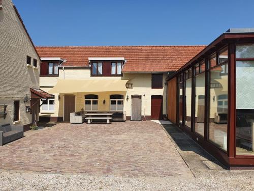 a courtyard of a house with a bench in front of it at Hoeve Cobelli in Noorbeek