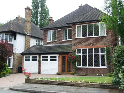 a large brick house with white garage doors at Gayton Bed & Breakfast in Hampton in Arden