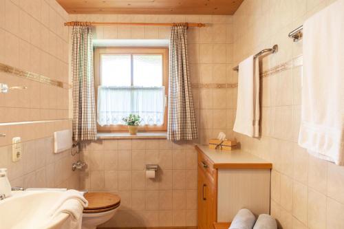 a bathroom with a toilet and a sink and a window at Ferienwohnung Alpenrose in Grainau
