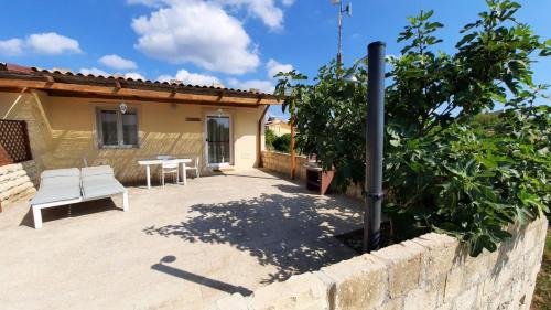 a patio in front of a house with a white bench at Residence Del Tellaro in Noto Marina