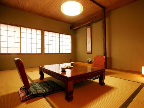 a dining room with a wooden table and a chair at Park Lodge Sekine in Myoko