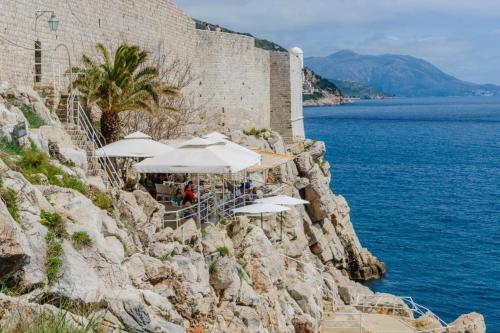 eine Gruppe von Sonnenschirmen auf einer Klippe am Meer in der Unterkunft Apartment Sympa in Dubrovnik
