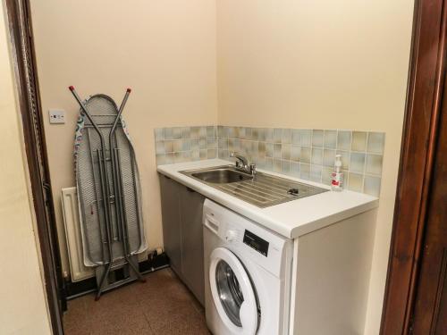 a laundry room with a sink and a washing machine at The Coach House in Allanton