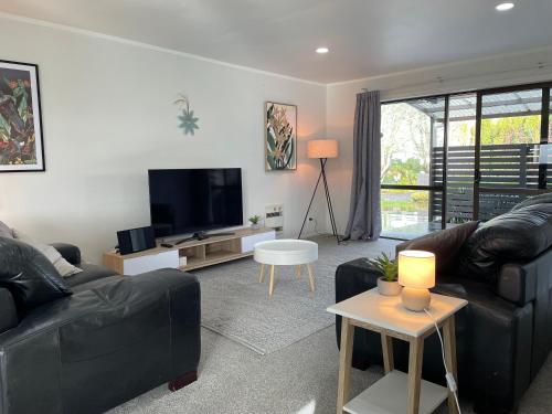 a living room with a black couch and a tv at Modern apartment- rural outlook, central Cambridge in Cambridge