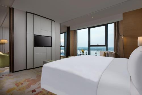 a bedroom with a large white bed and a television at Holiday Inn Nanjing Harbour by IHG in Nanjing