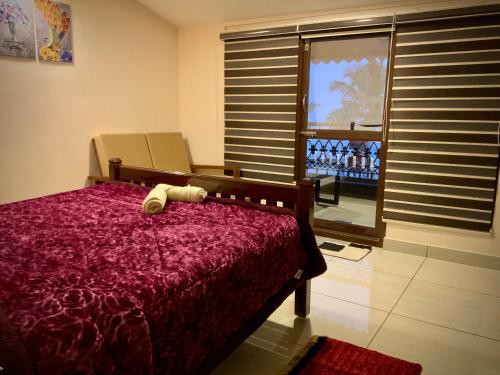 a bedroom with a bed with a red comforter and a window at Mermaid Island Beach Resorts in Puducherry