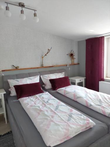 1 Schlafzimmer mit 2 Betten und roten Kissen in der Unterkunft Ferienwohnung Lotte in Felgentreu