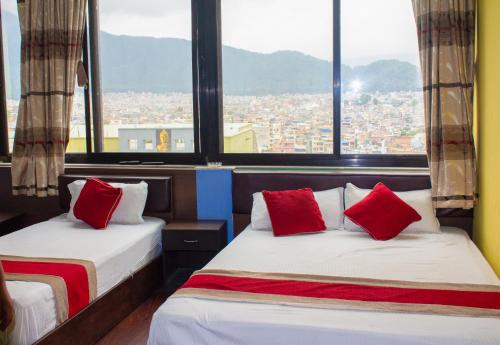 two beds with red pillows in a room with windows at Hotel Om in Kathmandu