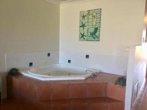 y baño con bañera y suelo de baldosa. en Villa 21 The Coral Cove Resort, en Elliott Heads