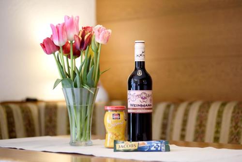 a bottle of wine and a vase of flowers on a table at Haus Wegener in Bad Sassendorf
