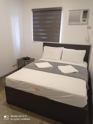 Una cama con sábanas blancas y almohadas en un dormitorio en 8 Zhensen Inn, en Bacoor