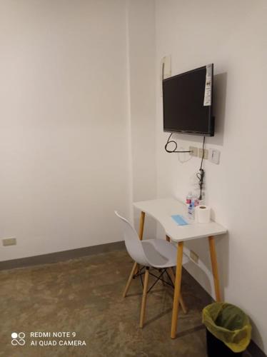 Cette chambre dispose d'un bureau, d'une télévision et d'une chaise. dans l'établissement 8 Zhensen Inn, à Bacoor