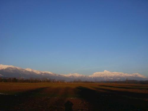 a field with snow capped mountains in the distance at Romantická chalupa pod Vysokými Tatrami in Liptovský Hrádok