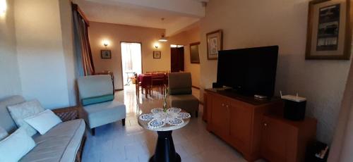 a living room with a couch and a tv at Villa de luxe avec piscine a 200m de la plage in Flic-en-Flac