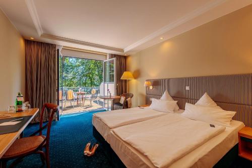 ein Hotelzimmer mit einem Bett, einem Schreibtisch und einem Balkon in der Unterkunft INSELHOTEL Potsdam in Potsdam