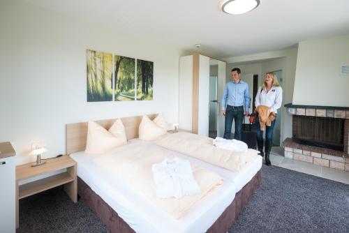 a man and woman standing in a bedroom with a large bed at Landhotel Kristall in Bad Marienberg