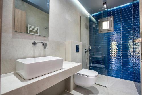 bagno con lavandino, servizi igienici e piastrelle blu di Oikos Daretsou a Theológos