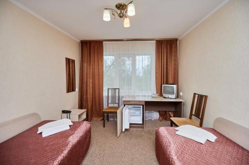 a hotel room with two beds and a desk at Olginskaya Hotel in Pskov
