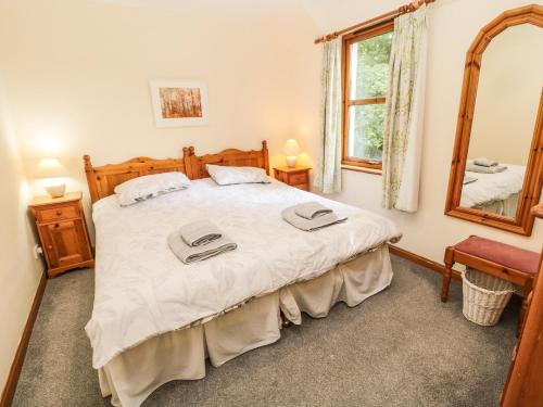 a bedroom with a large bed and a mirror at Gardener's Cottage in Allanton