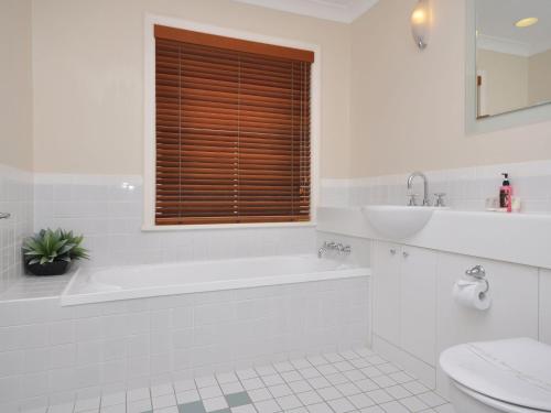 a bathroom with a tub and a sink and a toilet at Villa 3br Vista Villa located within Cypress Lakes Resort in Pokolbin