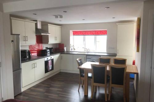 a kitchen with a table and chairs and a kitchen with white cabinets at Beautiful Sea view, Entire 2 bed Apartment, Portrush centre West Strand BeachView in Portrush