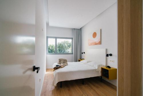 a white bedroom with a bed and a window at El Naranjito de Triana in Seville