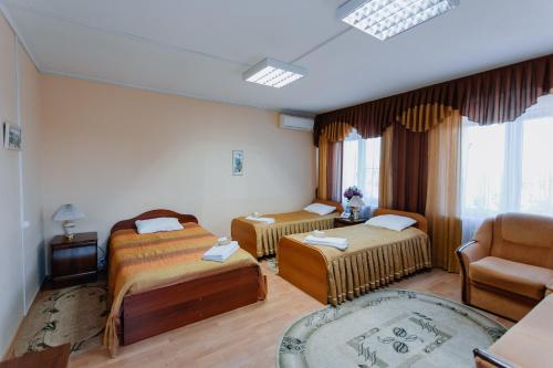 una habitación de hotel con 2 camas y una silla en Comfort Hotel, en Lipetsk