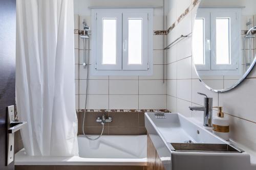 a bathroom with a tub and a sink and a mirror at Althea Apartment in Skopelos Town
