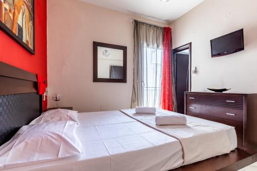 a bedroom with a large white bed and a red wall at Althea Apartment in Skopelos Town