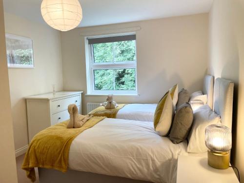 a bedroom with two beds and a window at BEST PRICE - AMAZING 2 Bed 2 Bath - 4 Singles or Super King beds, 10 min walk to city centre, 5 minute walk to Mayflower theatre, Smart Tv, Ensuite, Balcony, FREE PARKING in Southampton