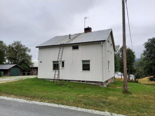 a white house with a metal roof on the side of the road at Messlingen 160 in Funäsdalen