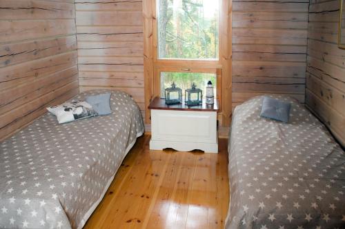 two beds in a room with wooden walls and a window at Villa Bergholmen in Taalintehdas